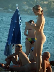 Young nude beauty with perky boobs plays near the sea